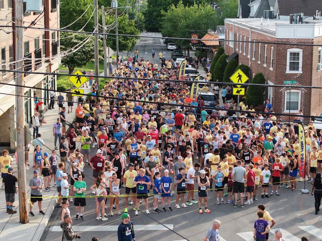 Aerial view of hundreds of runners filling the street at the Jenkintown Sunset 5K start