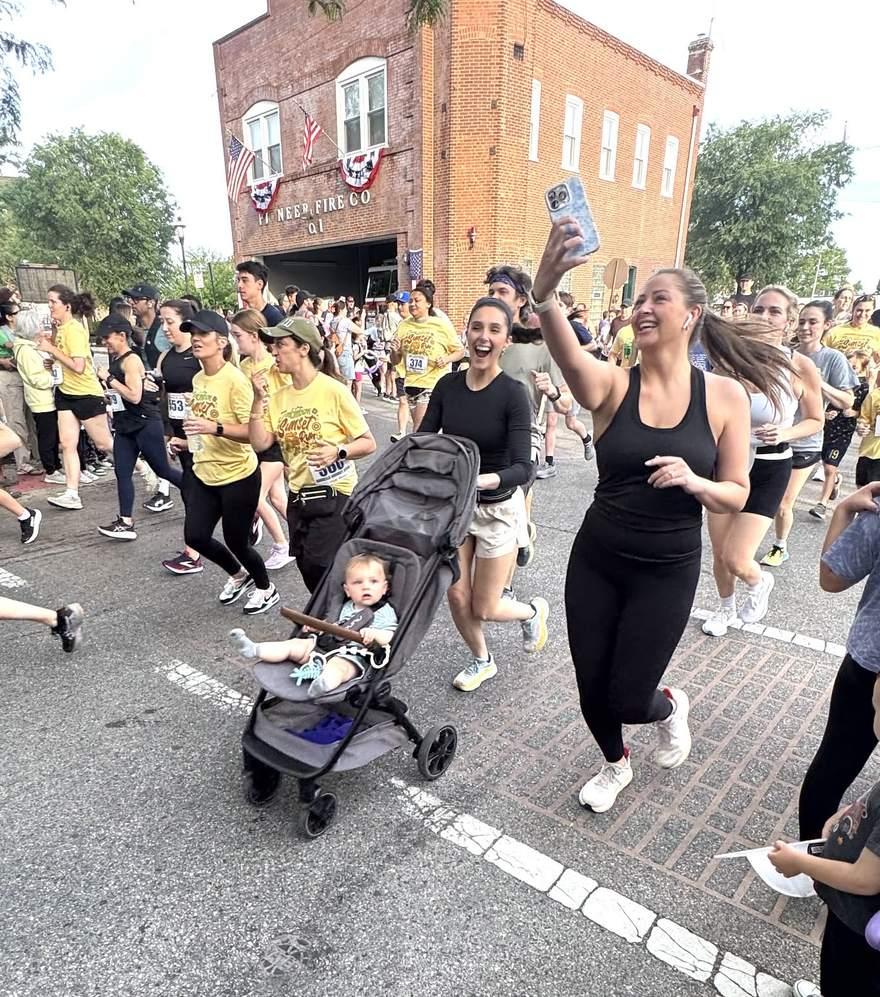 Runners and a stroller passing the Pioneer Fire Company at the Jenkintown Sunset 5K